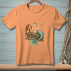 Peach t-shirt with a mermaid holding a martini with a pufferfish nearby.