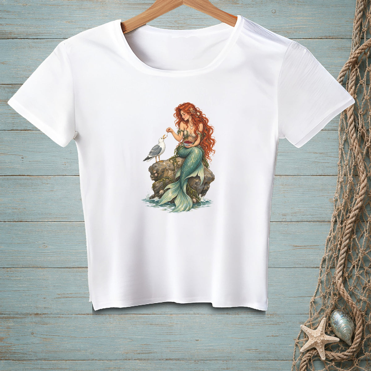White t-shirt with a mermaid feeding a seagull on a rock design.