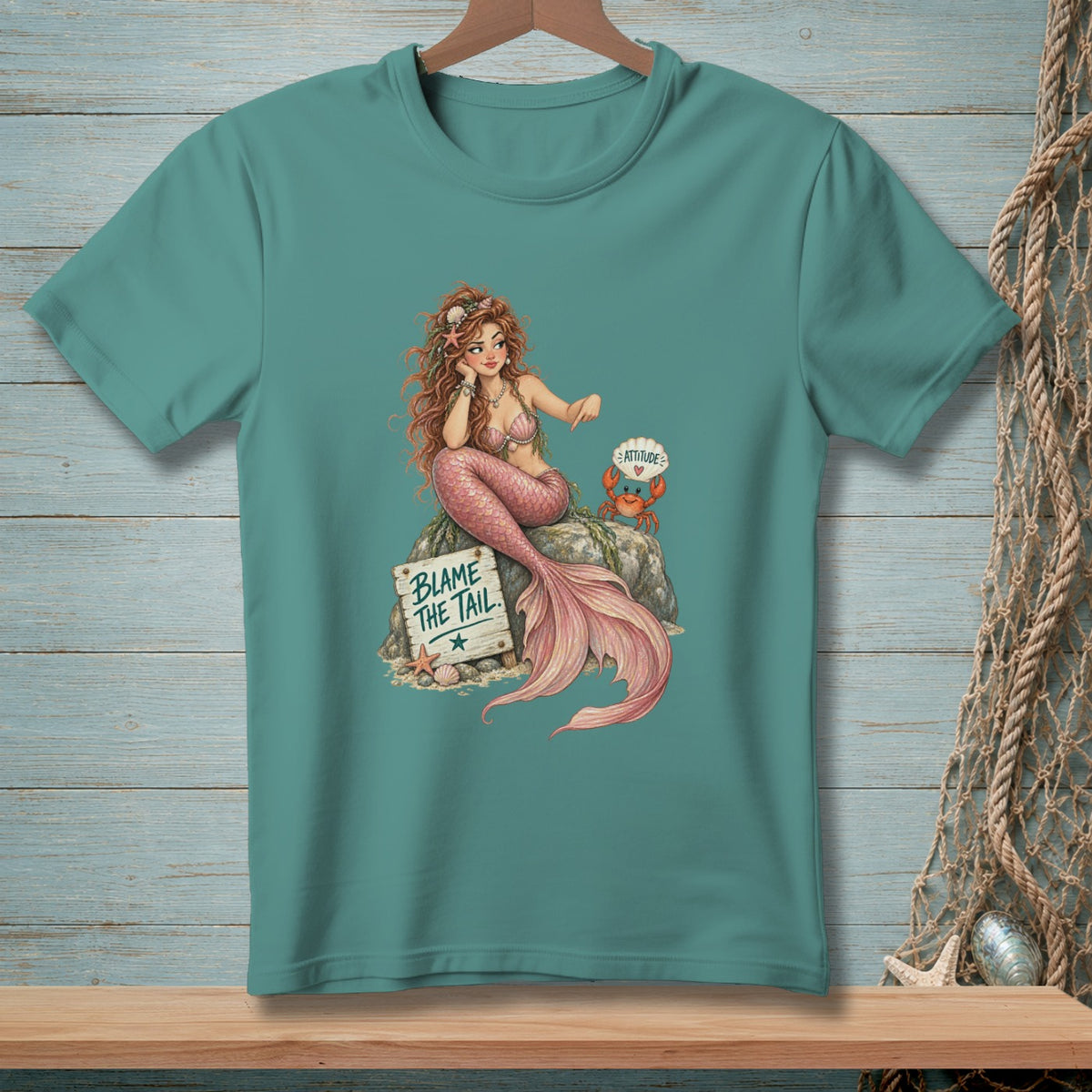 Mermaid sitting on a rock with a crab and sign that says "Blame the Tail".