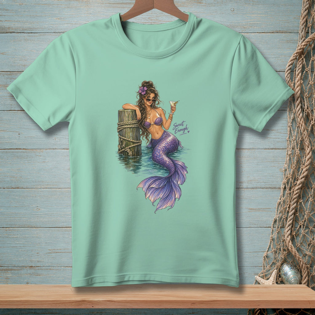 Mermaid with purple tail holding a cocktail next to a wooden post, text "Sweet Enough".