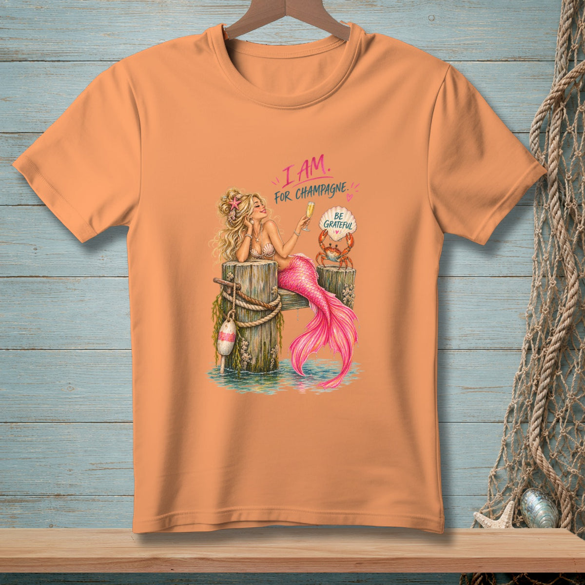 T-shirt graphic with a mermaid and crab, text "I AM. FOR CHAMPAGNE. BE GRATEFUL."