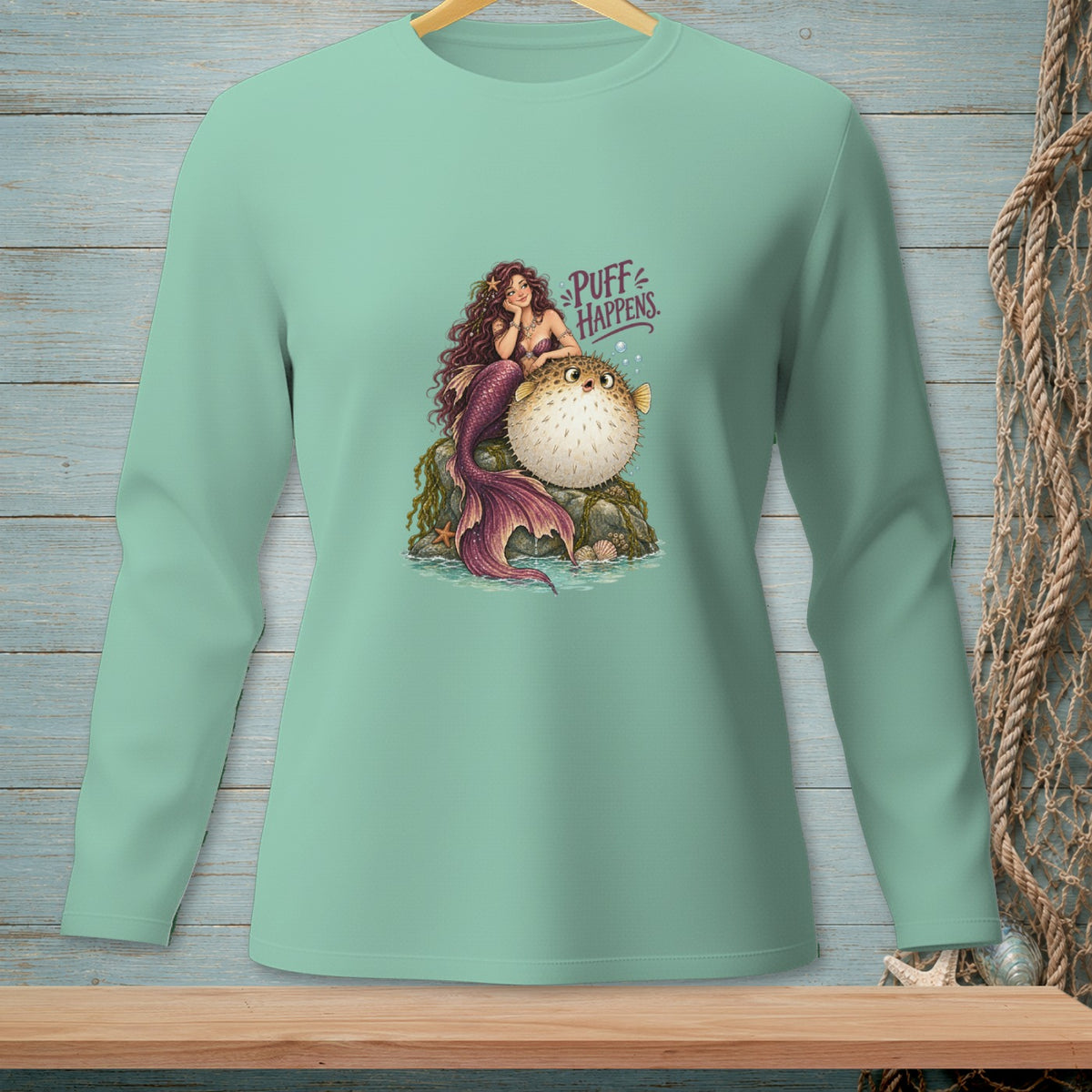 Mermaid sitting on a rock with a pufferfish, text reads "Puff Happens."