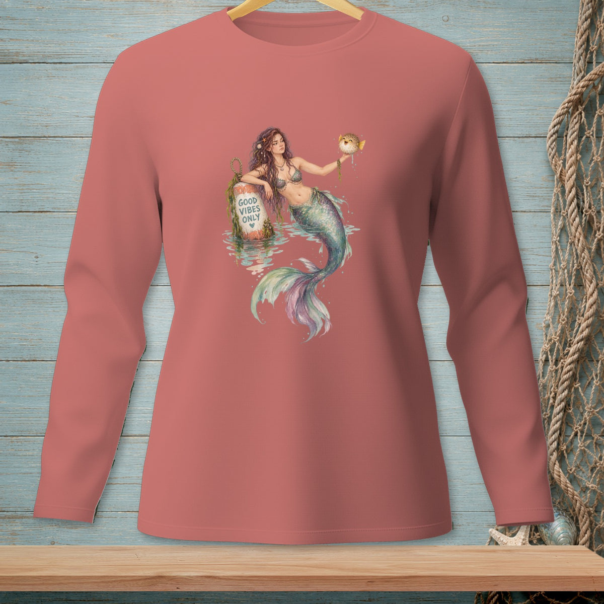Mermaid holding pufferfish, leaning on buoy with "GOOD VIBES ONLY" text.