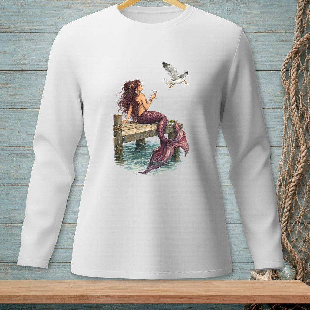 Mermaid on dock holding drink with seagull flying near, on white long-sleeve shirt.