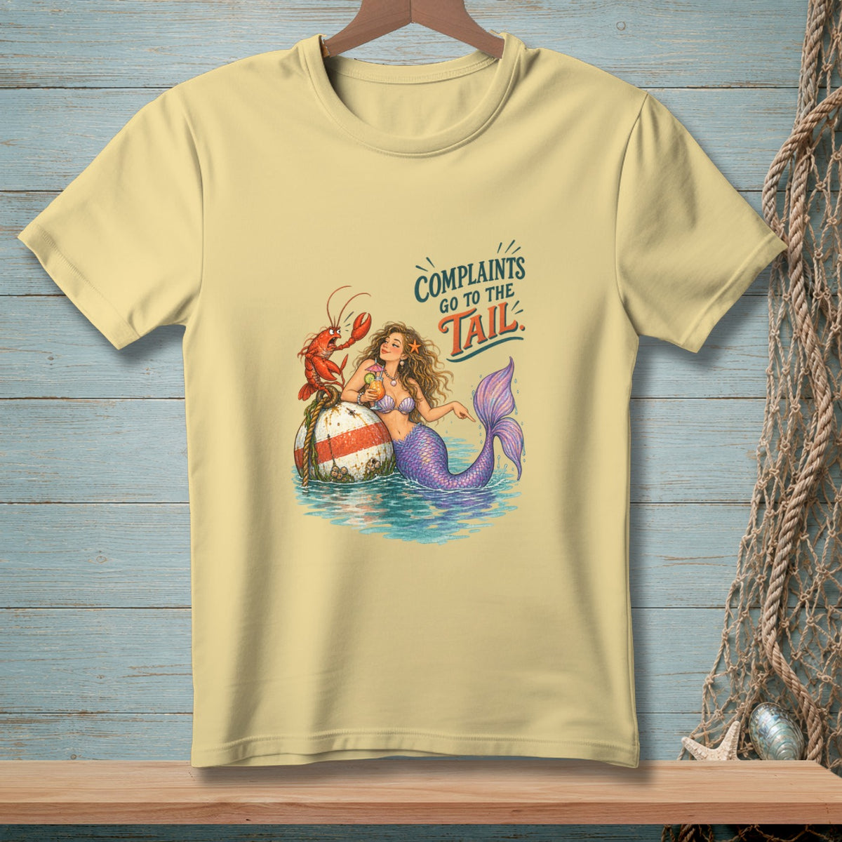 Mermaid with lobster on buoy, "Complaints Go to the Tail" text on light yellow t-shirt.