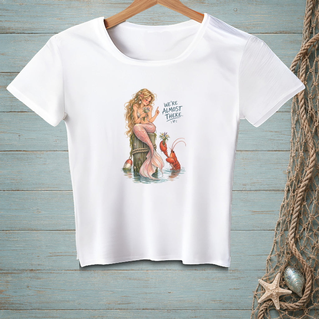 White t-shirt with mermaid and lobster illustration and text "We're almost there."