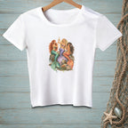 White t-shirt with graphic of three mermaids on rocks, holding champagne glasses.