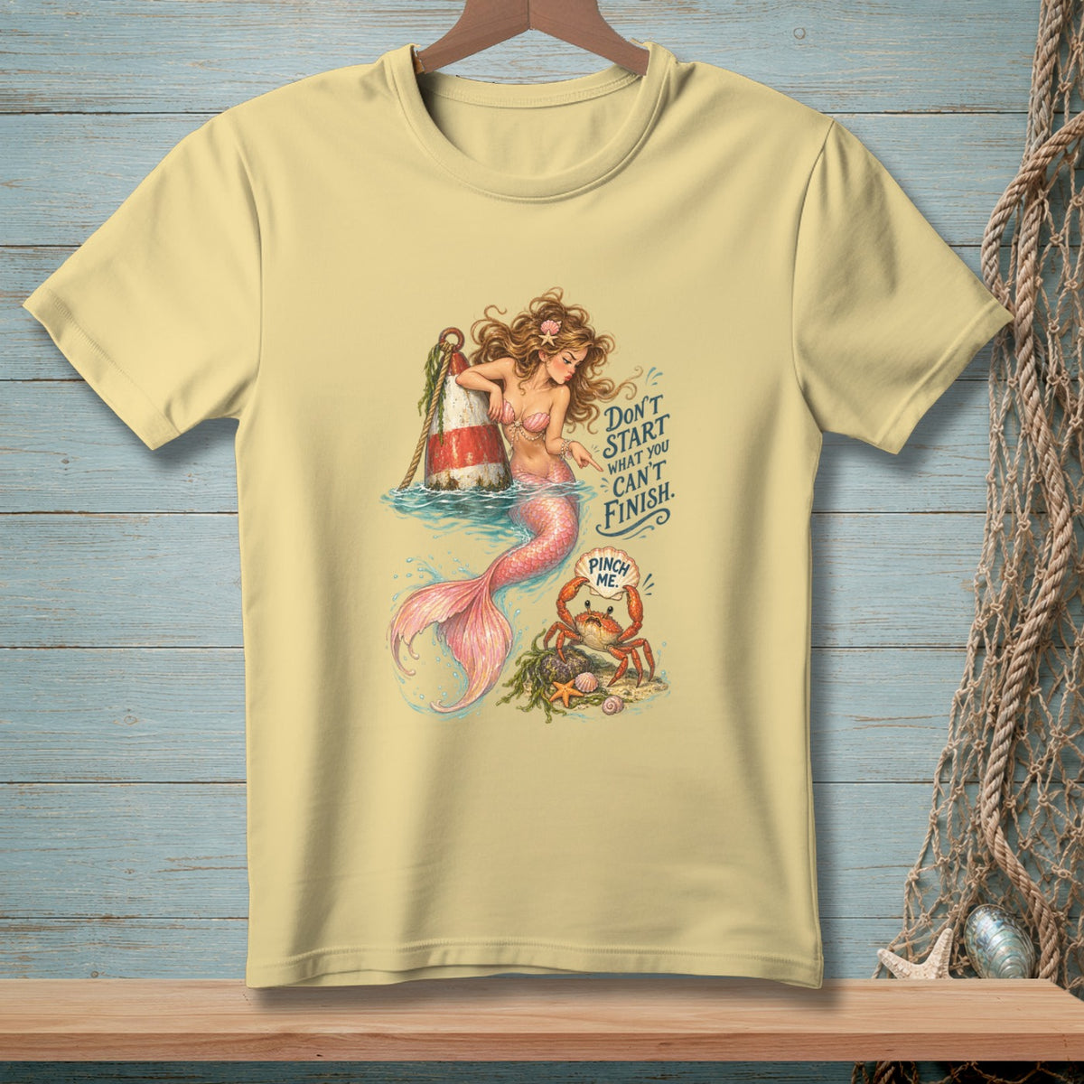 Mermaid and crab illustration on a light yellow t-shirt with text.