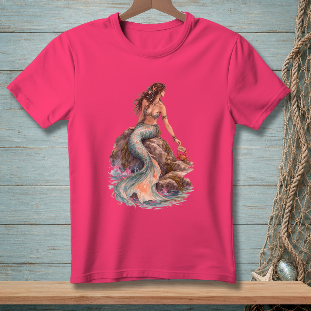 Pink t-shirt with a detailed illustration of a mermaid sitting on rocks with a crab holding a "smile" sign.
