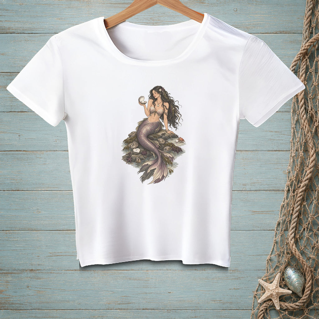 White t-shirt featuring a mermaid holding a seashell, seated on rocks with shells.