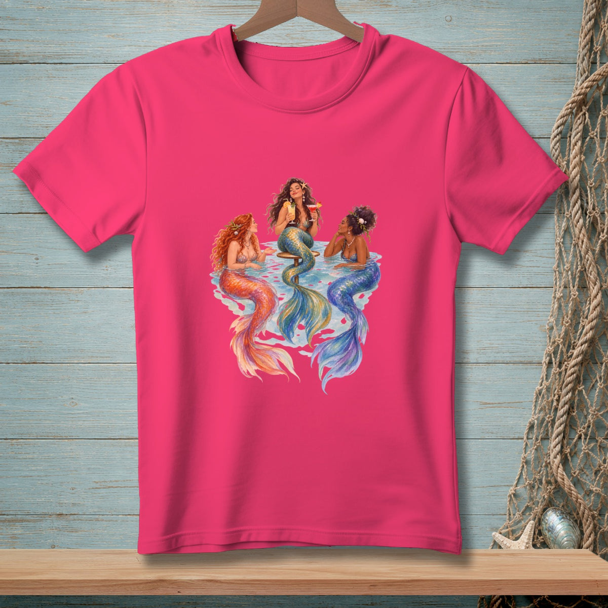 Three mermaids with colorful tails sit in water, one holding a drink.