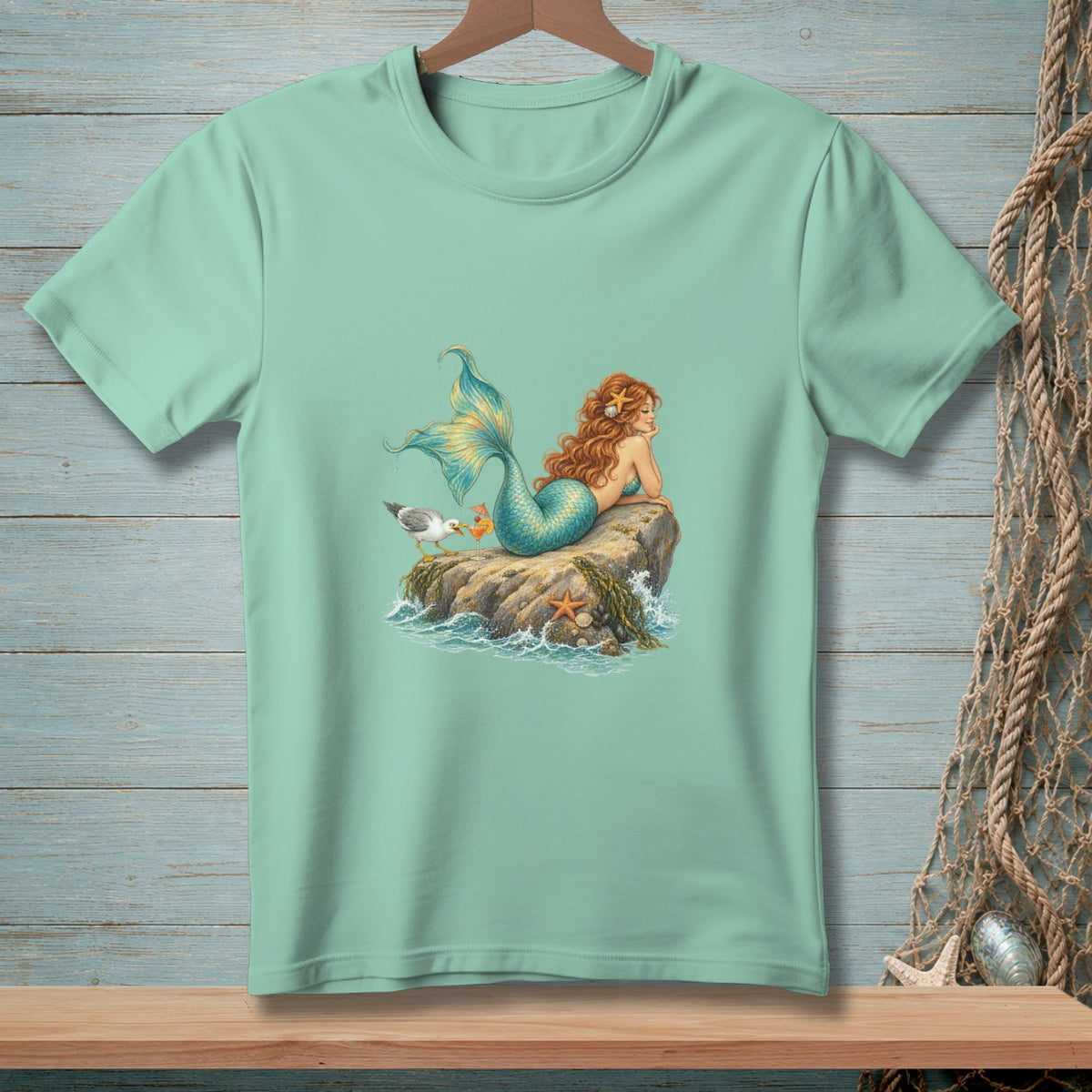 Mint t-shirt featuring a mermaid on a rock with a seagull.