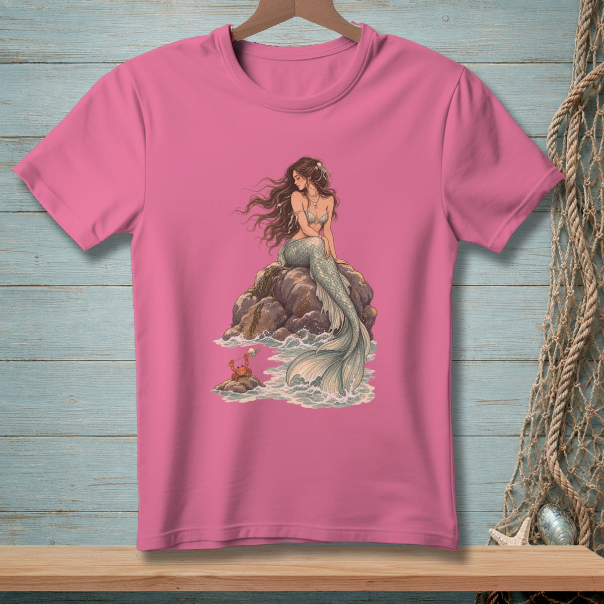 Pink t-shirt with a mermaid sitting on a rock with a crab nearby.