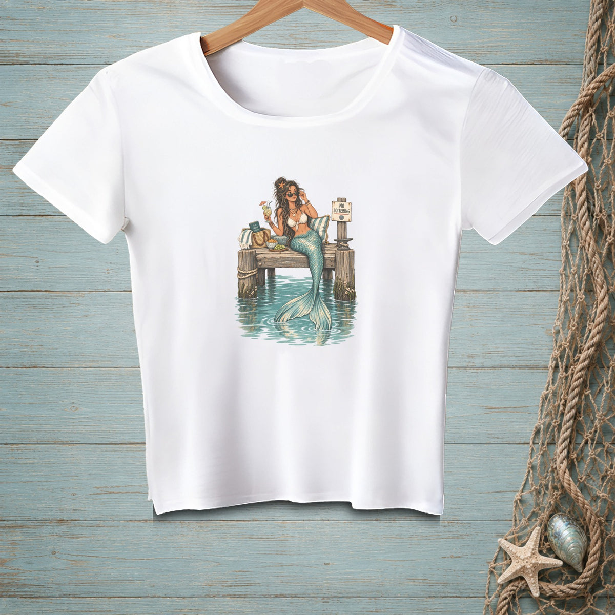 White t-shirt with a mermaid sitting on a dock with a drink and a sign.
