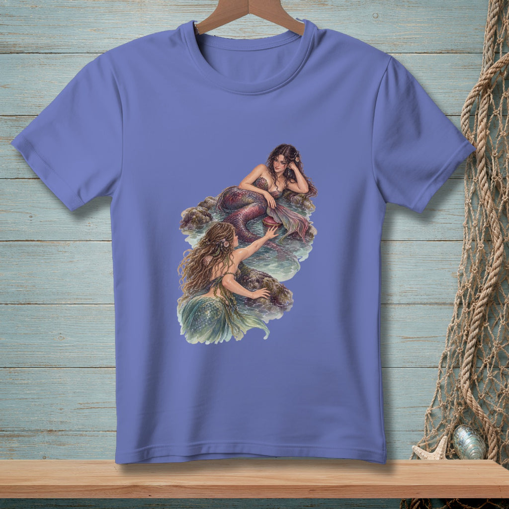 Illustration of two mermaids on rocks in water printed on a purple t-shirt.