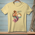 Mermaid with pufferfish on yellow t-shirt, text reads "That's a lot of drama per inch."