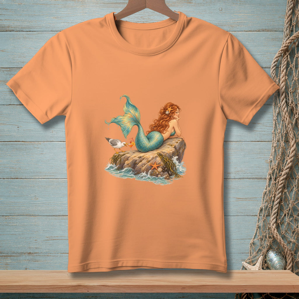 Orange t-shirt with illustration of a mermaid lounging on a rock with a seagull.