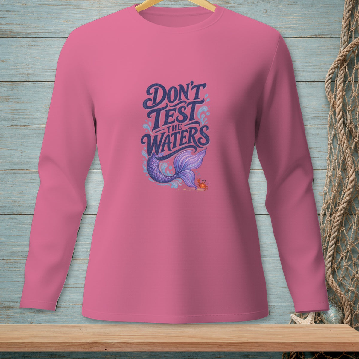 Pink long-sleeve shirt with "Don't Test the Waters" text, mermaid, and crab graphic.