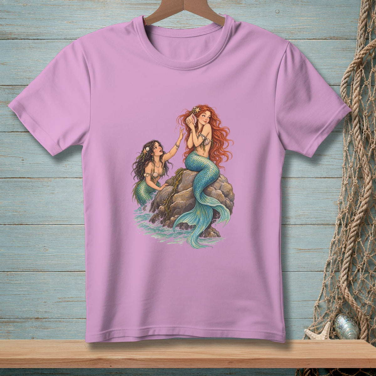 Two mermaids, one holding a shell to her ear, sit on rocks near the sea.