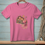 Pink t-shirt with illustration of a sleeping mermaid surrounded by colorful fish and coral.