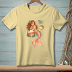 Light yellow t-shirt with a mermaid and pufferfish graphic saying "Well, somebody's puffy."