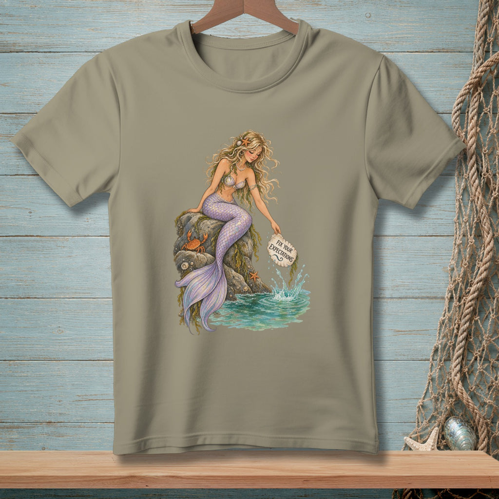 Mermaid sitting on rocks, holding a sign that says "Fix Your Expectations".