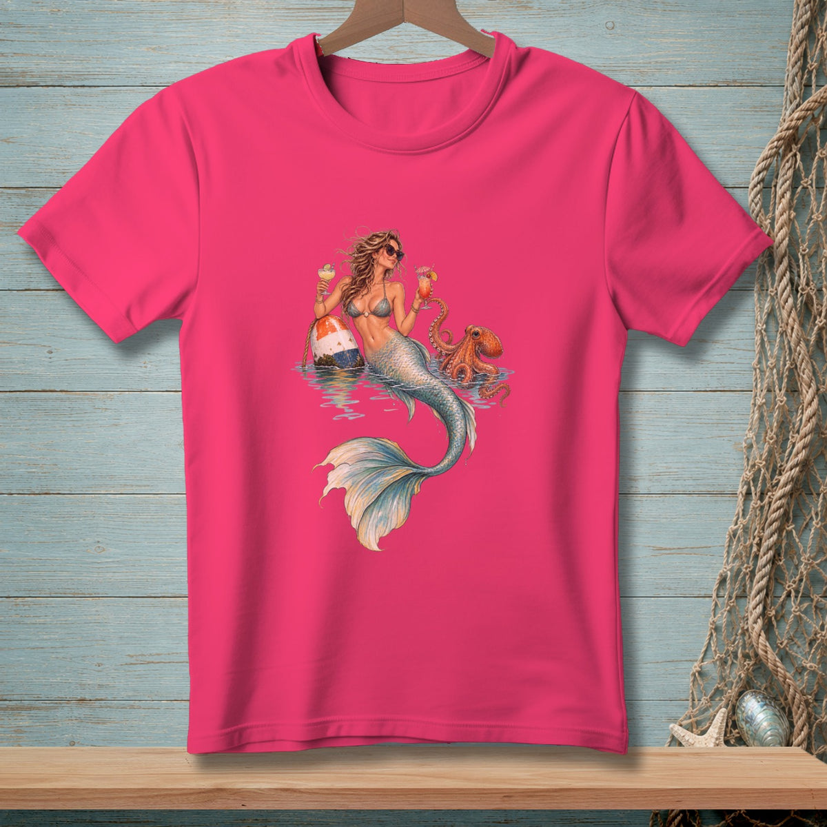 Pink t-shirt with a graphic of a mermaid, octopus, and a buoy in the water.