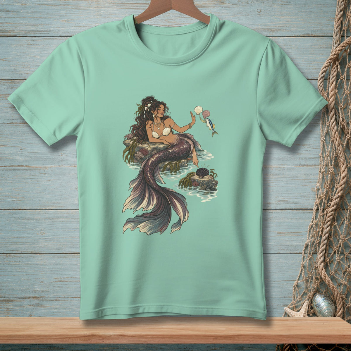 Mermaid holding seashells, with fish and shells on rocks.