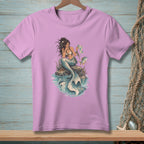 Mermaid sitting on a rock holding a map with a fish nearby.