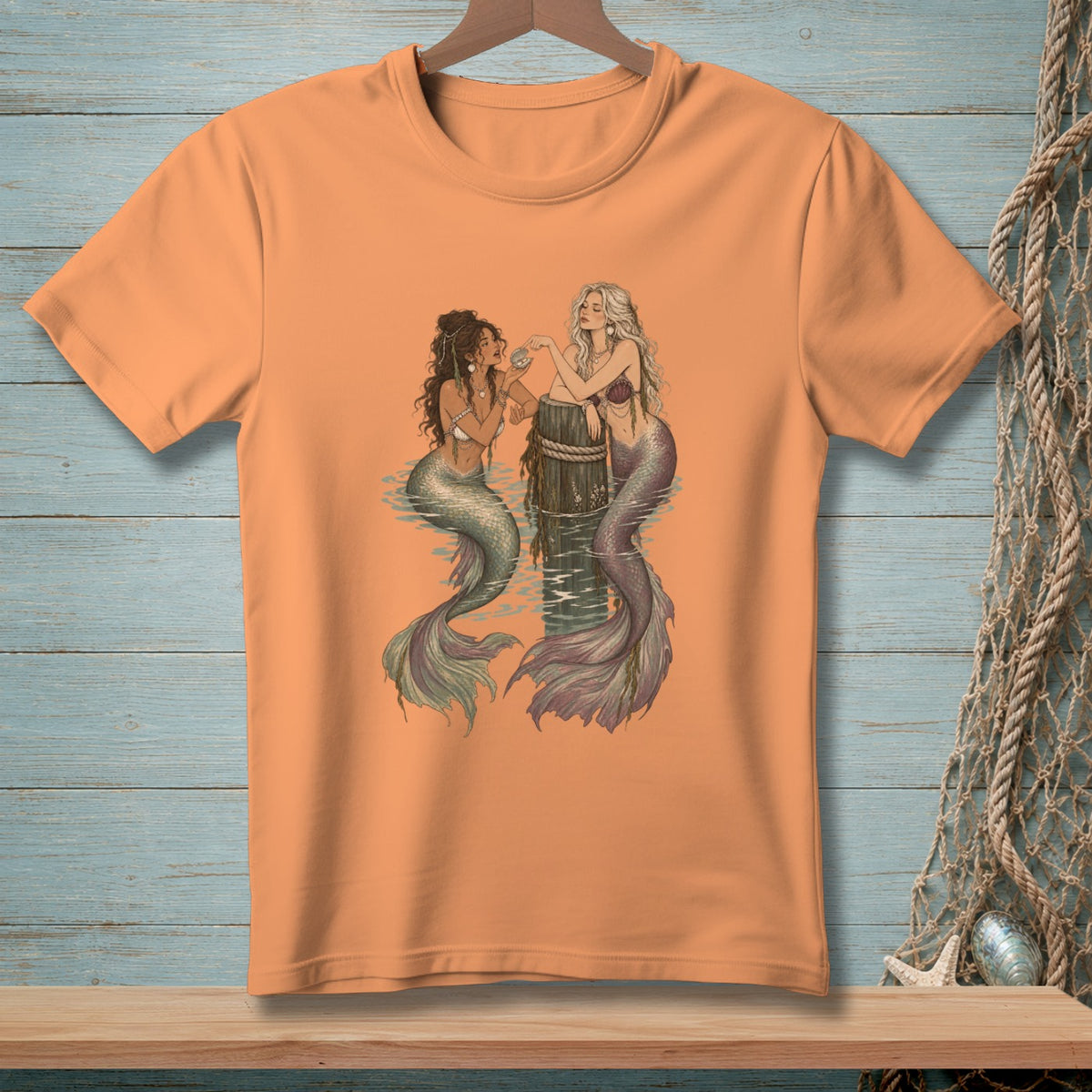 Two mermaids sitting on a wooden post in the water.