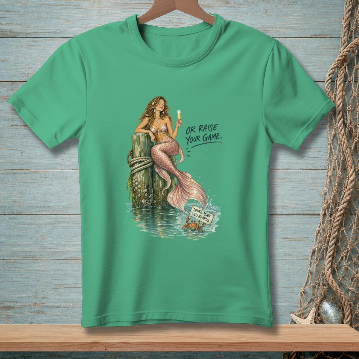Green t-shirt with a mermaid and crab graphic and text "Or Raise Your Game."