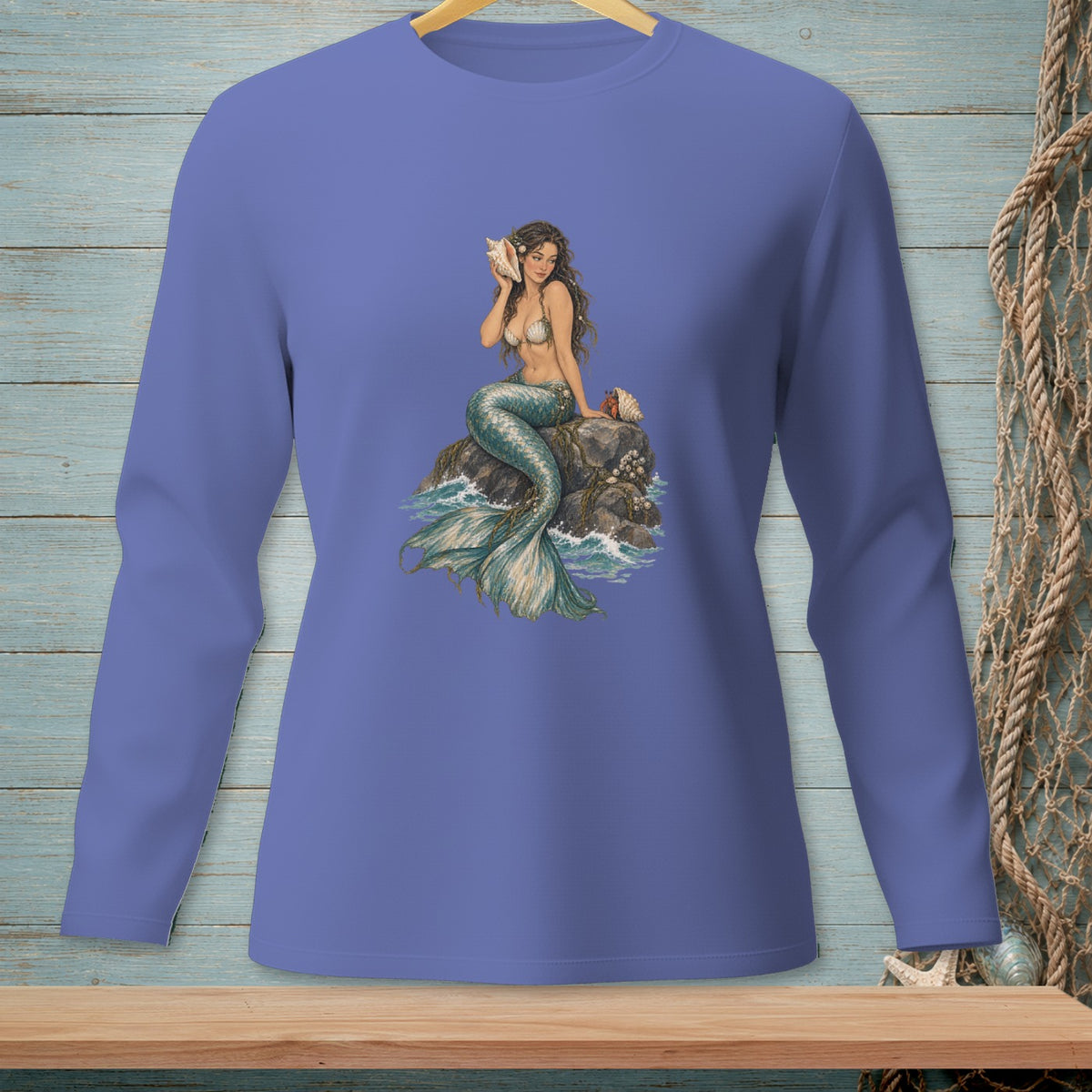 Long-sleeve shirt with a mermaid holding a seashell on a rock surrounded by water.