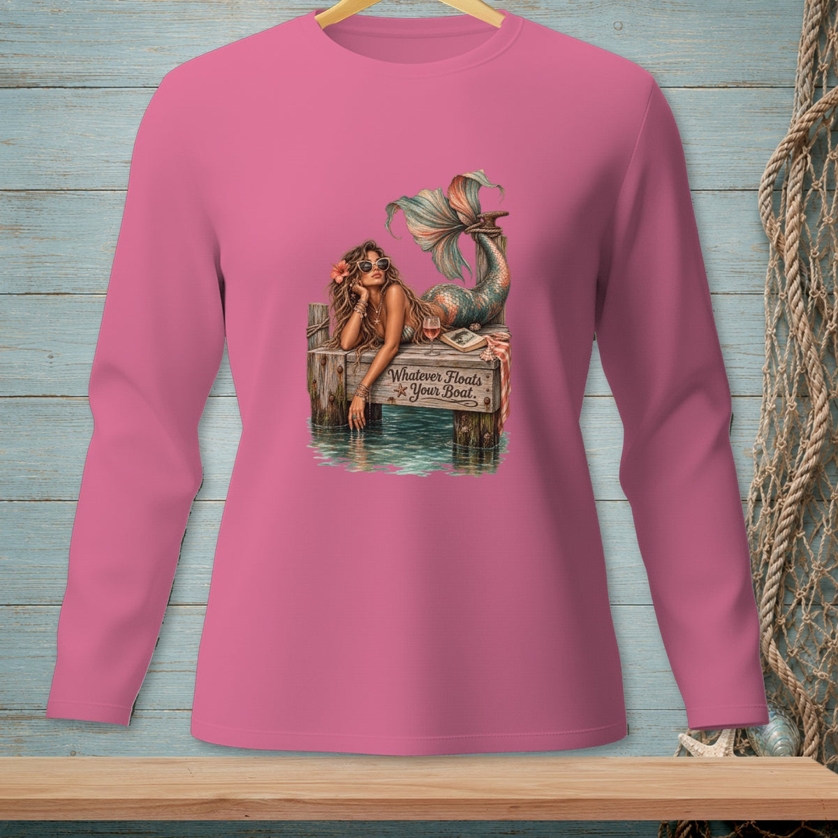 Mermaid on pier with text "Whatever Floats Your Boat" on pink long-sleeve shirt.