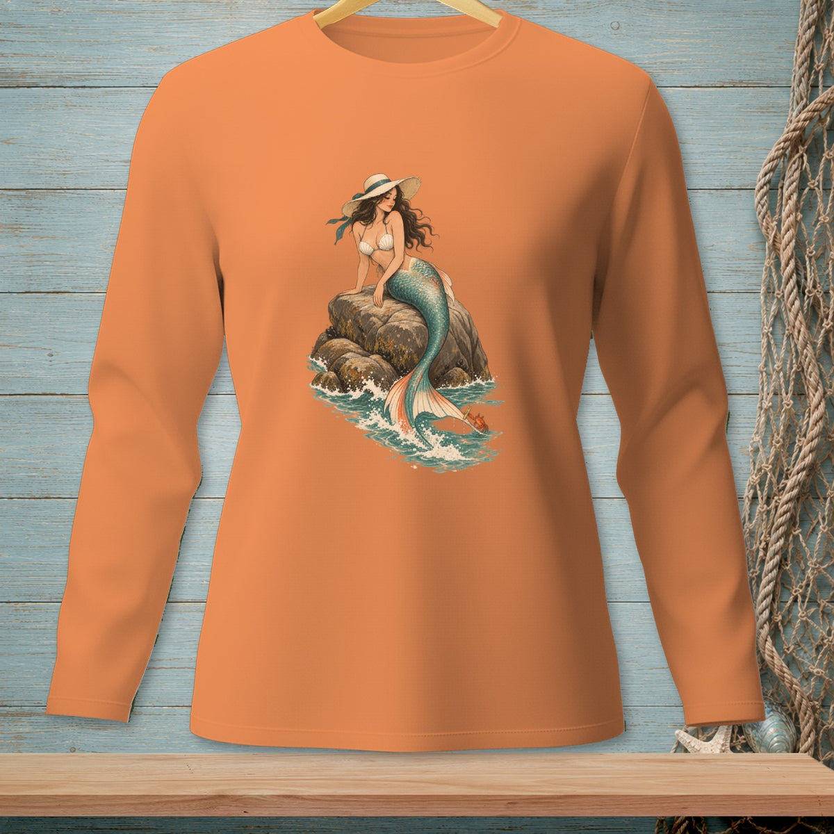 Long sleeve orange shirt with a graphic of a mermaid sitting on a rock.