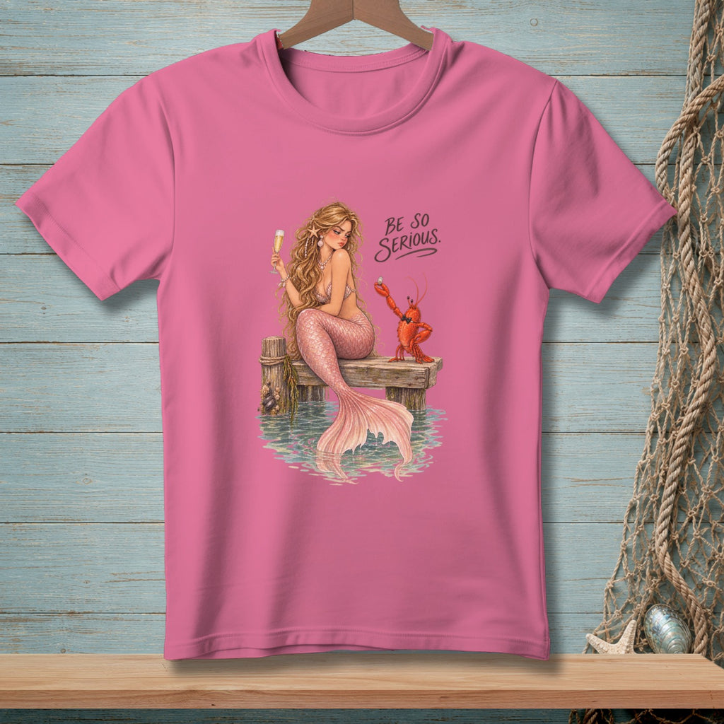 Pink t-shirt with illustration of a mermaid and lobster on a dock, text "Be So Serious."