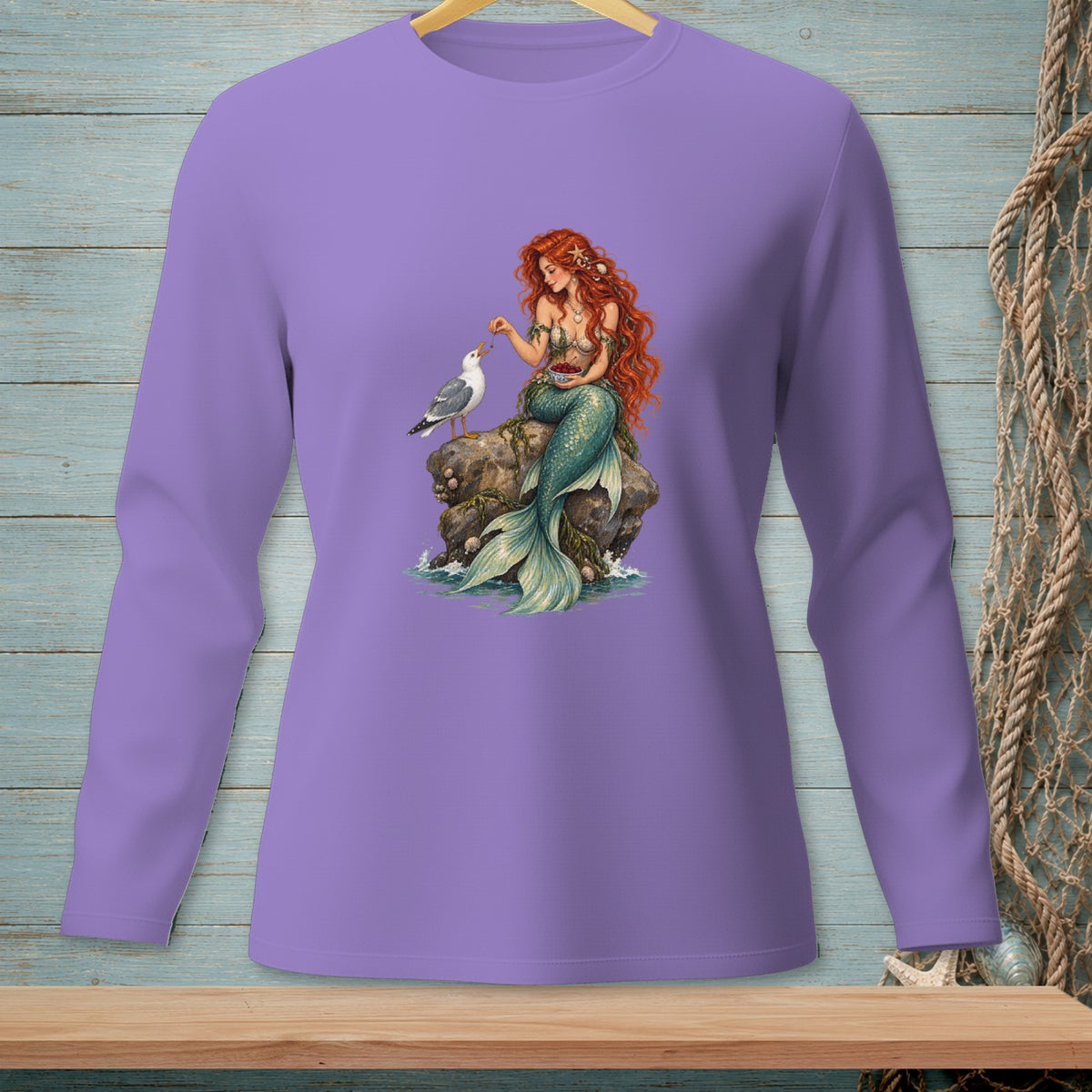 Lavender long-sleeve shirt with a mermaid feeding a seagull on a rock.