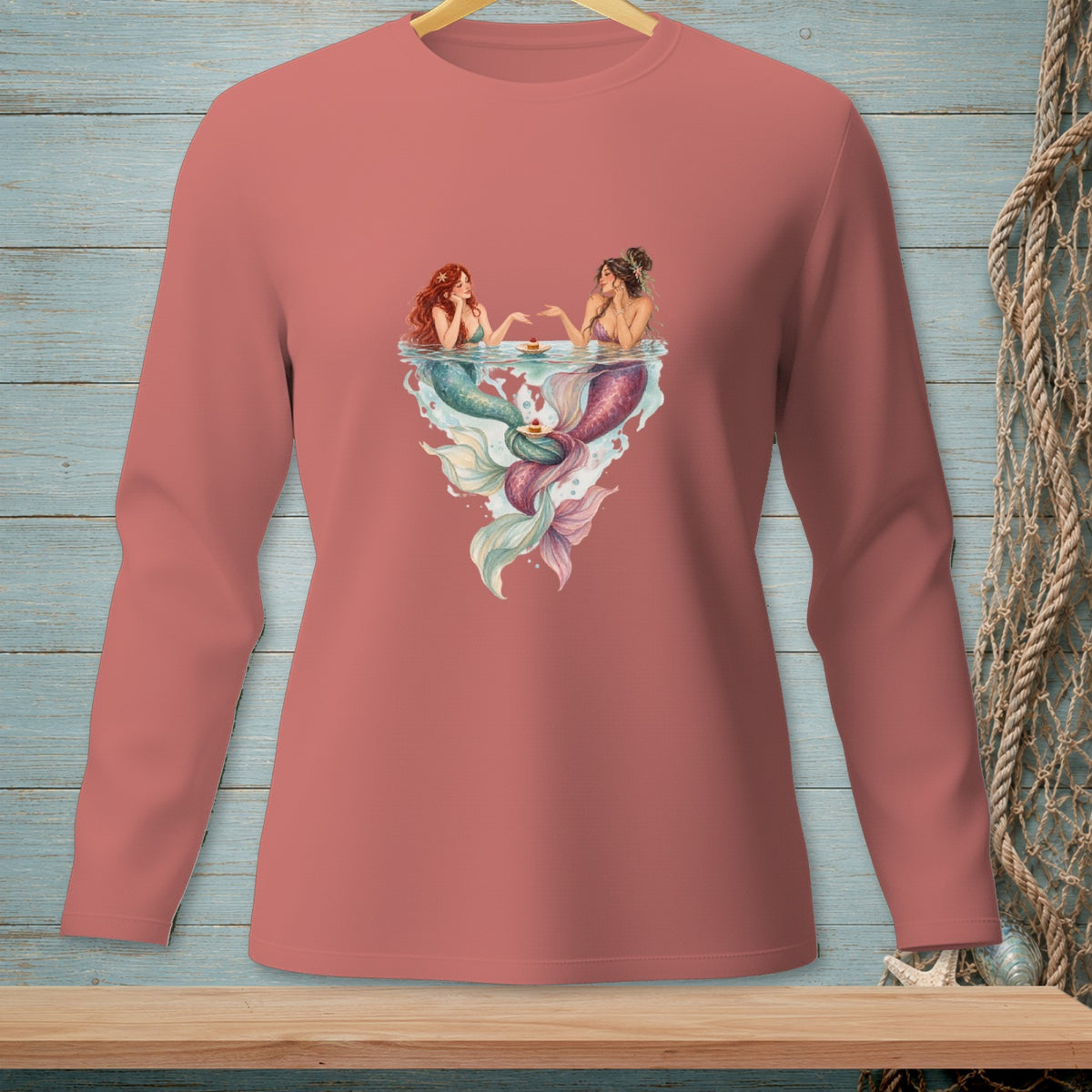 Two mermaids with tails swim in water, reaching for treats on small plates.