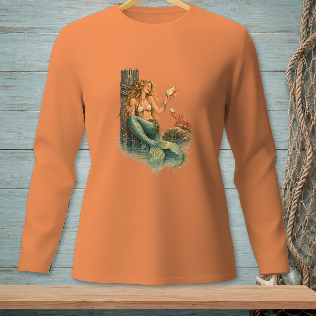 Mermaid holding seashell by dock with crab and starfish on orange long sleeve shirt.