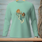 Two mermaids with teal tails share a drink on a wooden tray.