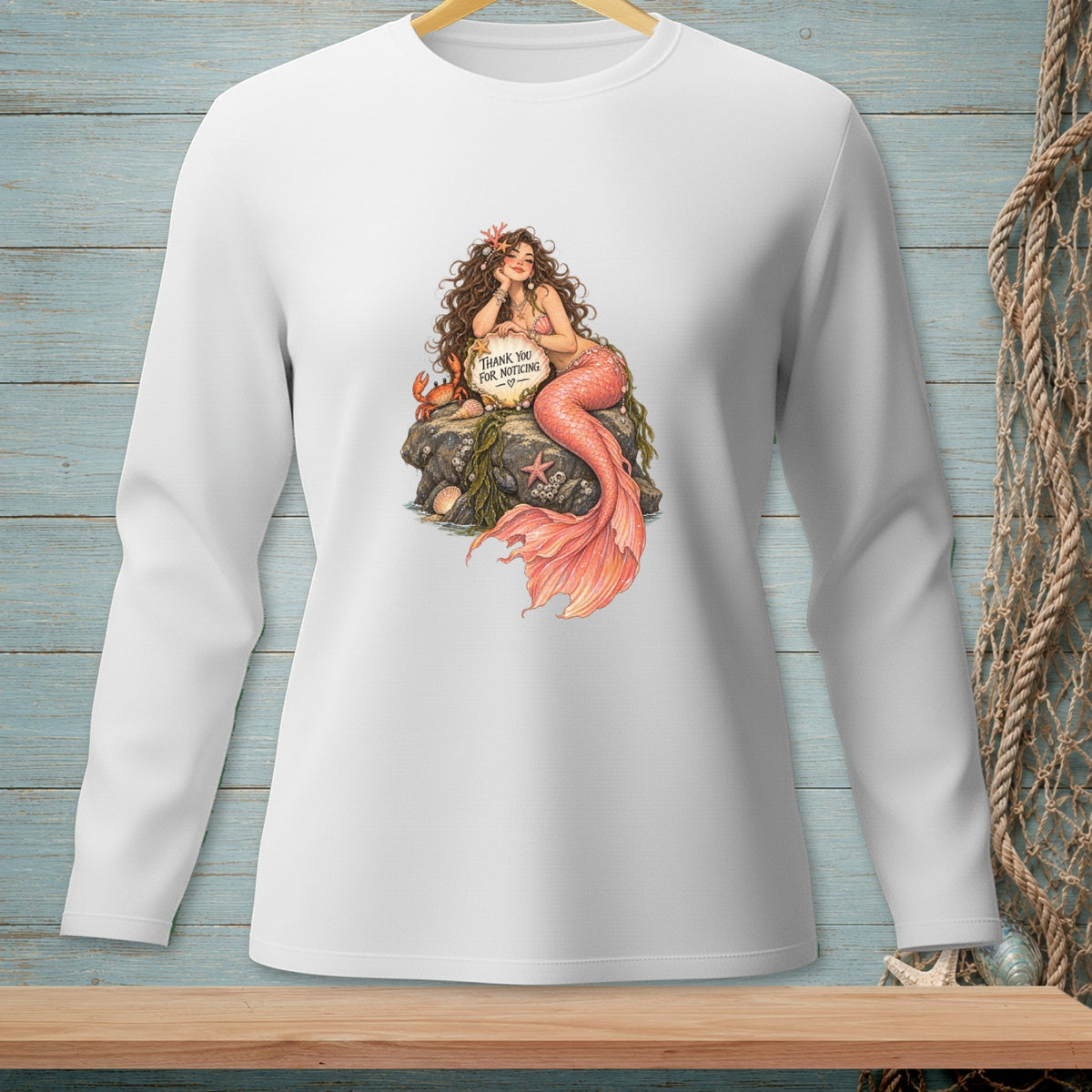 White long-sleeve shirt with mermaid, crab, and sign saying "Thank you for noticing."