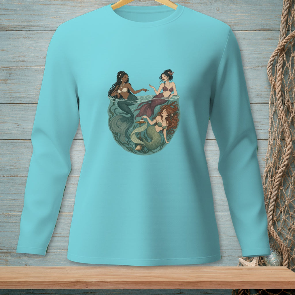 Three mermaids swimming in a circle with seaweed and shells in a teal long-sleeve shirt.