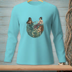Three mermaids swimming in a circle with seaweed and shells in a teal long-sleeve shirt.