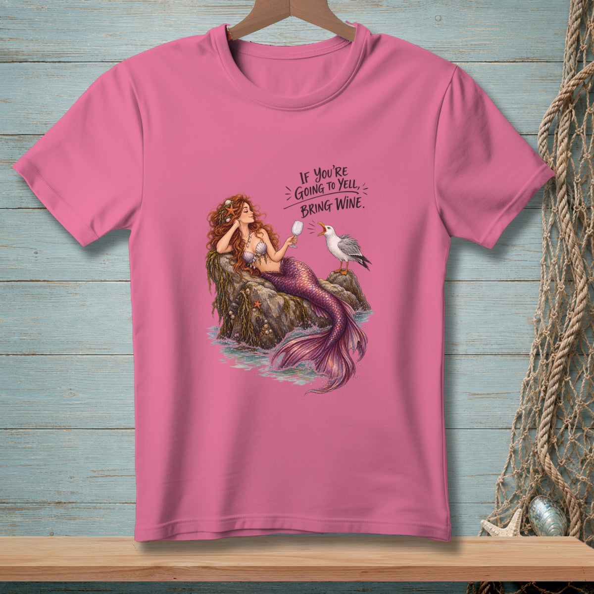 Pink t-shirt with illustration of a mermaid and seagull, text says "If you're going to yell, bring wine."