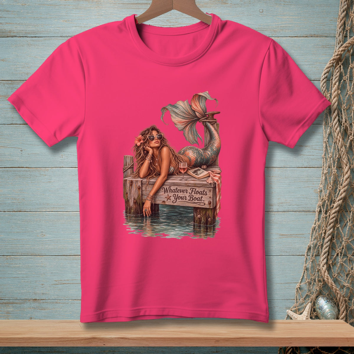 Pink t-shirt with mermaid on pier, reads "Whatever Floats Your Boat."