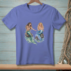 Two mermaids sit on rocks with waves crashing around them.