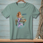Mermaid with wine and books on a dock, text reads "Handled".