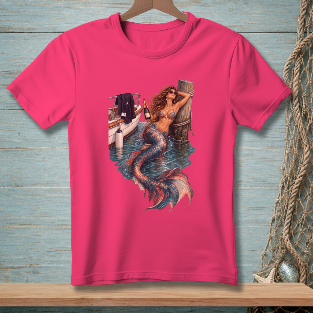Pink t-shirt with a graphic of a mermaid by a boat holding a champagne bottle.