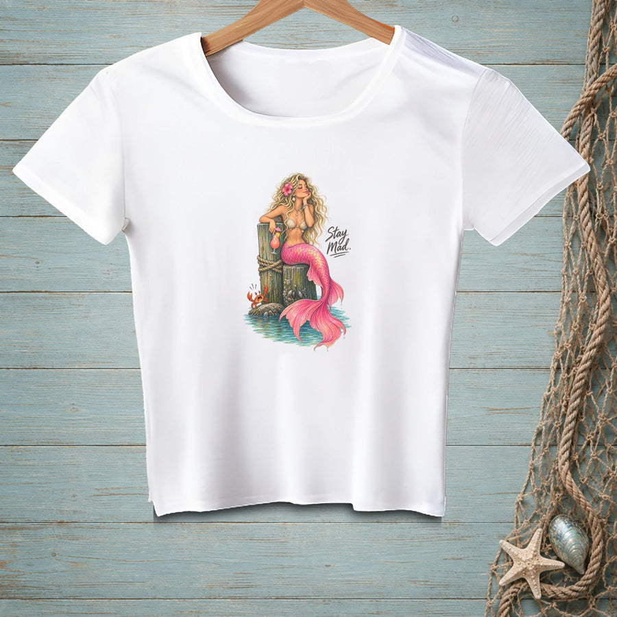 White t-shirt with graphic of mermaid on pier, text "Stay Mad".