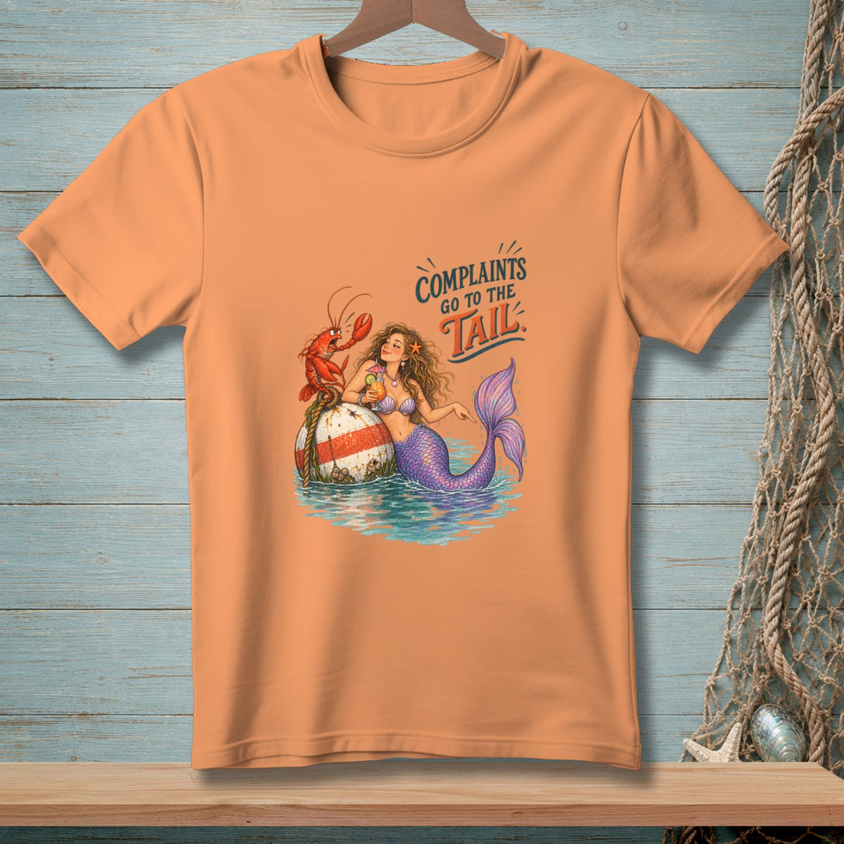 Peach t-shirt with mermaid, lobster, buoy, and "Complaints go to the tail" text.
