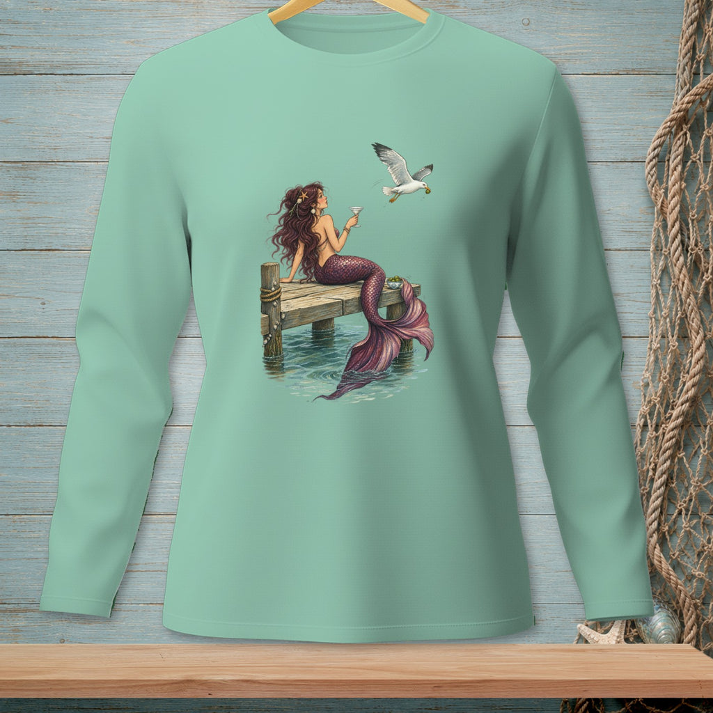 Mermaid with purple tail holding a drink on a dock with a seagull.